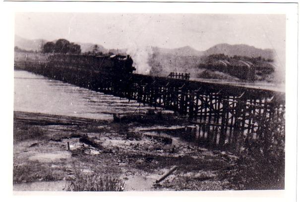 A train on the wooden bridge near Tamarkan with steel bridge in the background.